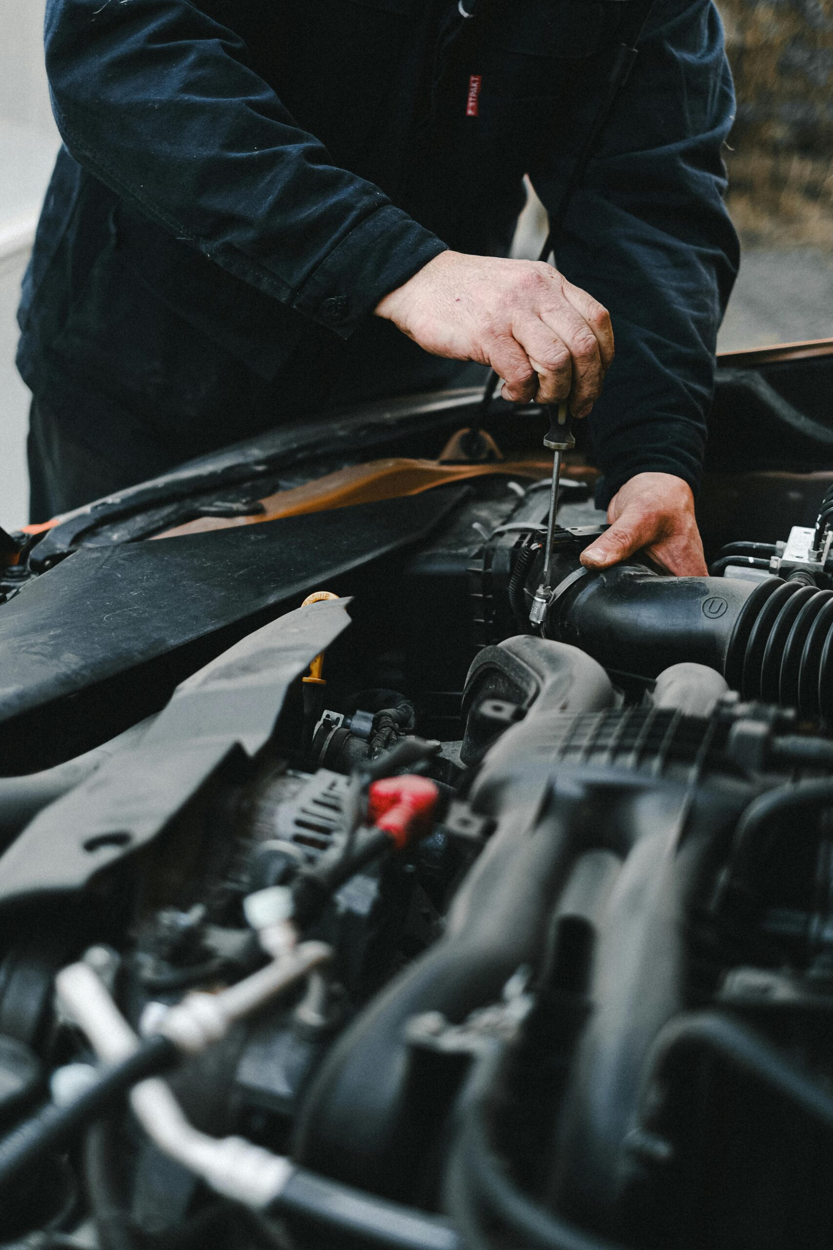 Detailed shot of mechanic working on a car engine showing hands and tools.